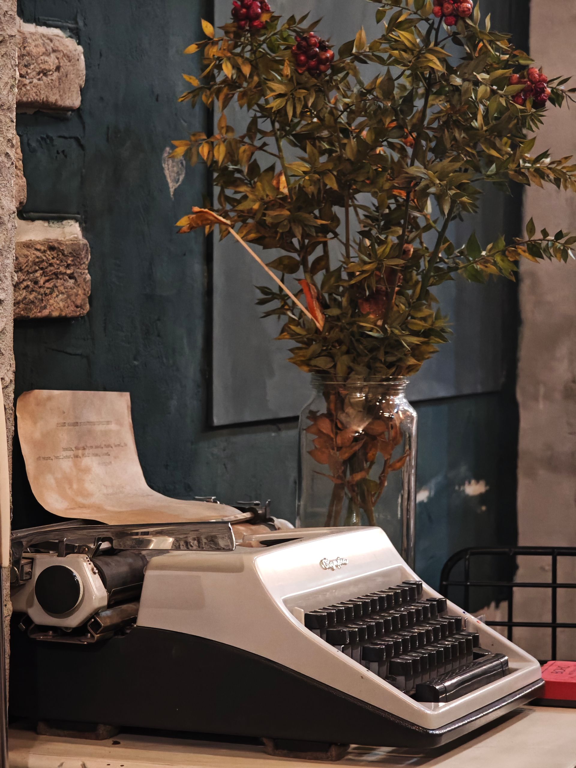 Cozy corner featuring a vintage typewriter and autumn foliage in a rustic setting.